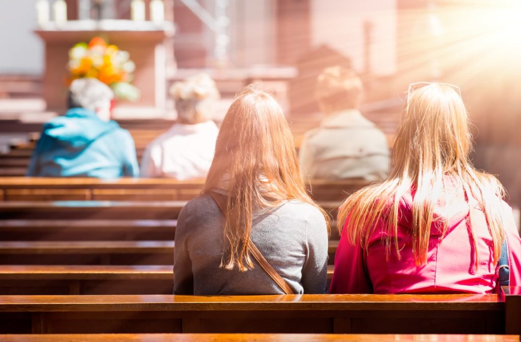 people sitting in church pews with the sun streaming in 