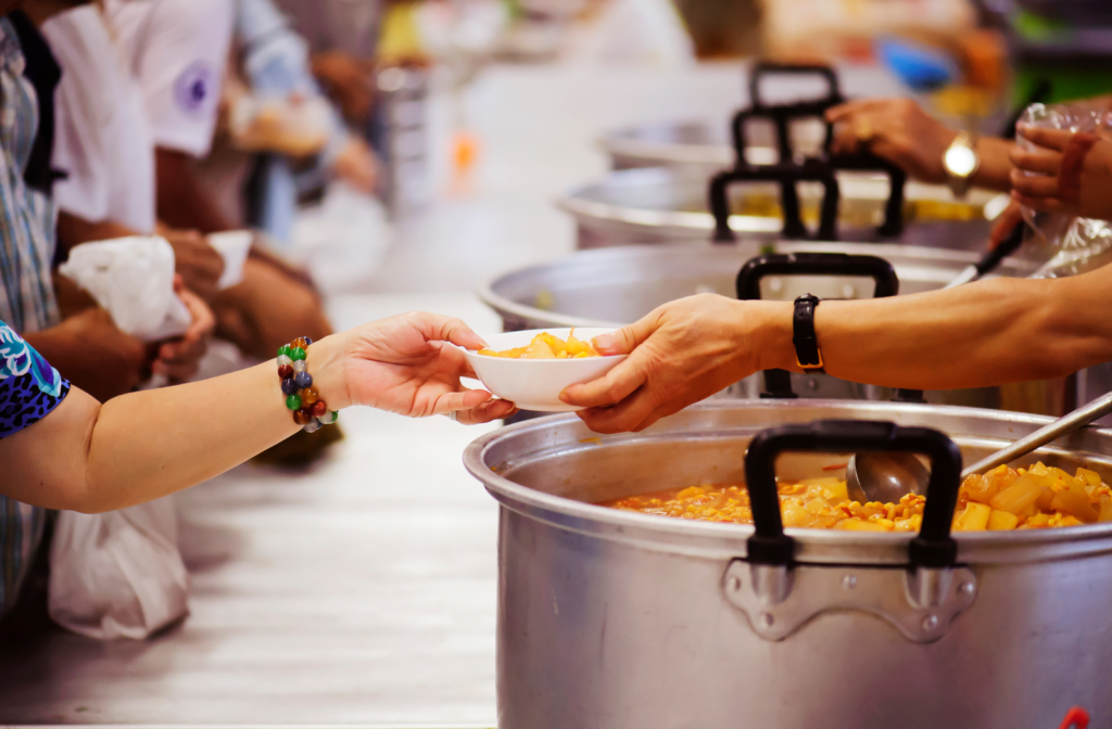 Kitchen volunteers serving meals from large pots of food