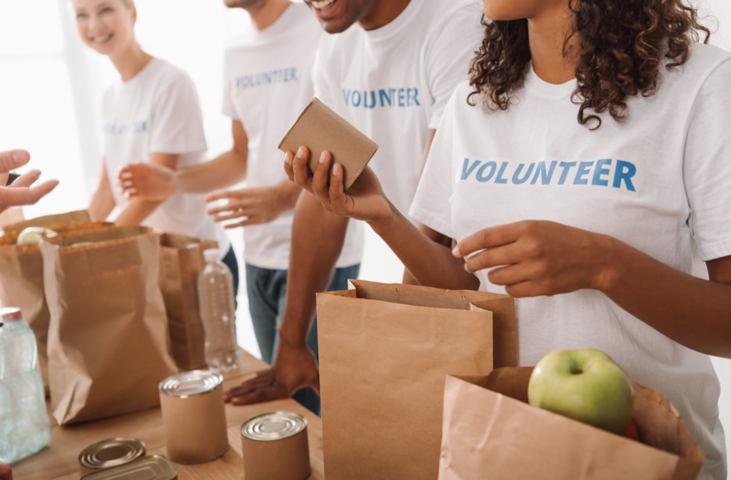 Happy young volunteers placing donation items in paper bags