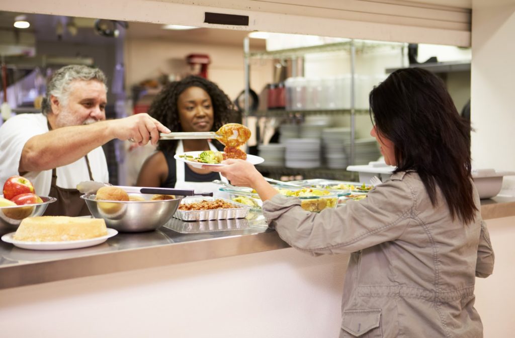 Kitchen staff serving food at homeless shelter.