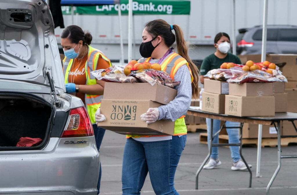 Women carrying food items to car for food bank
