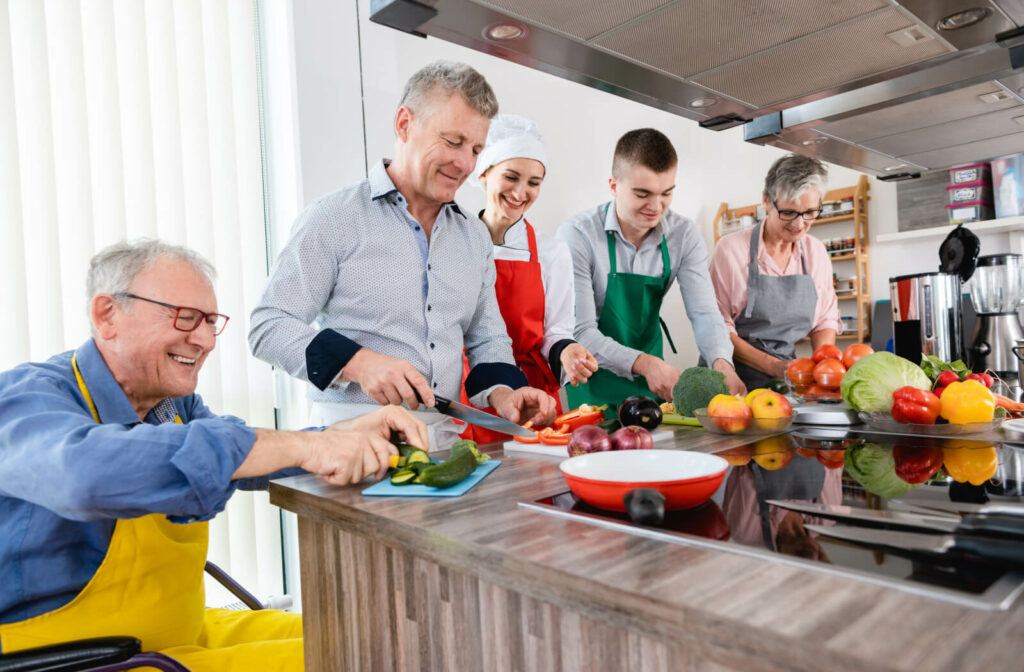A group of adults and chefs in a training kitchen with food.