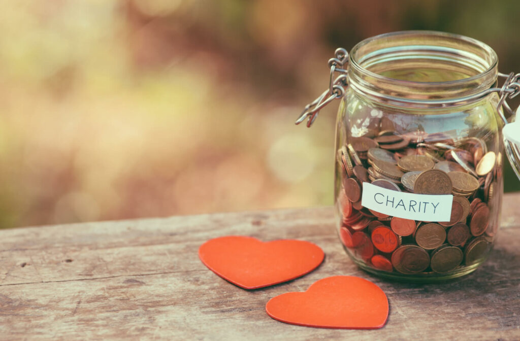 A jar full of coins for charity and 2 heart shapes in a table.