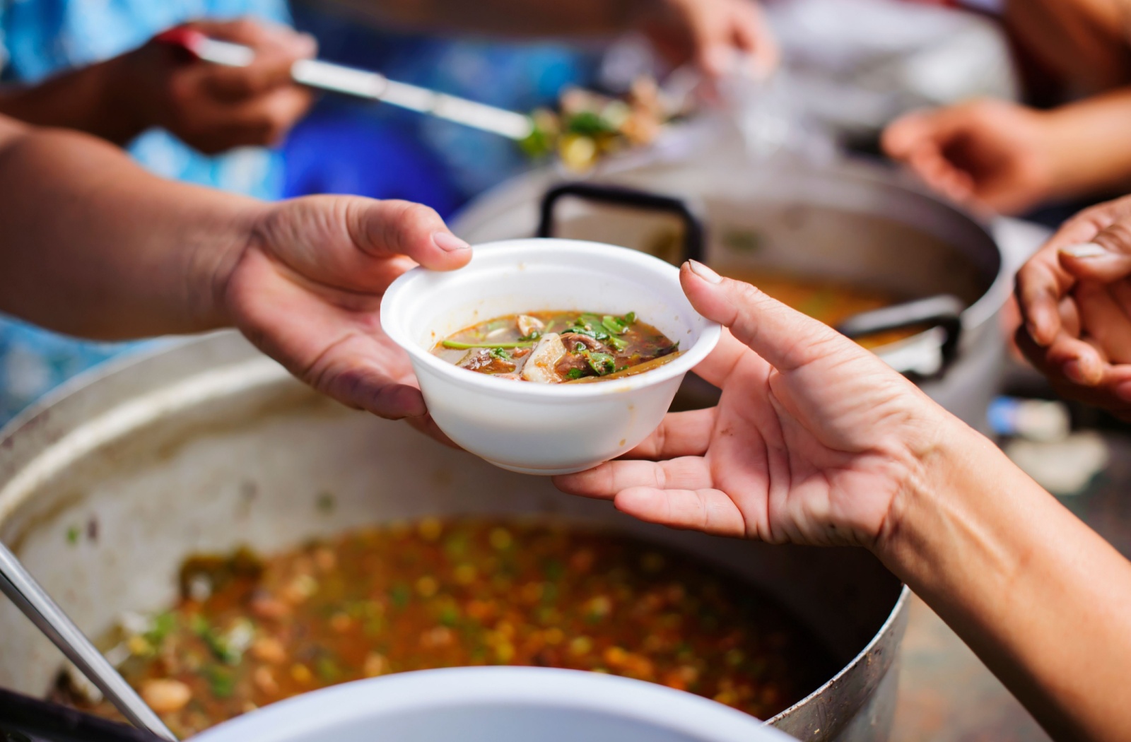 Volunteers handing out a bowl of food another person.
