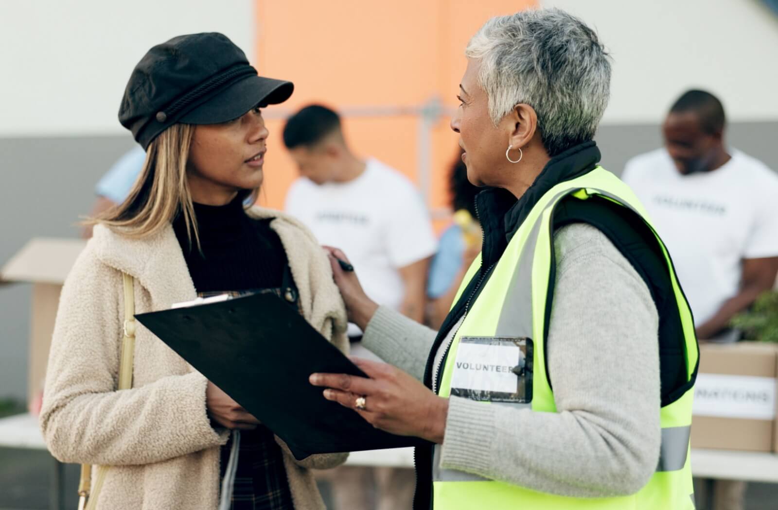 A volunteer coordinator talks with a community member during an event.
