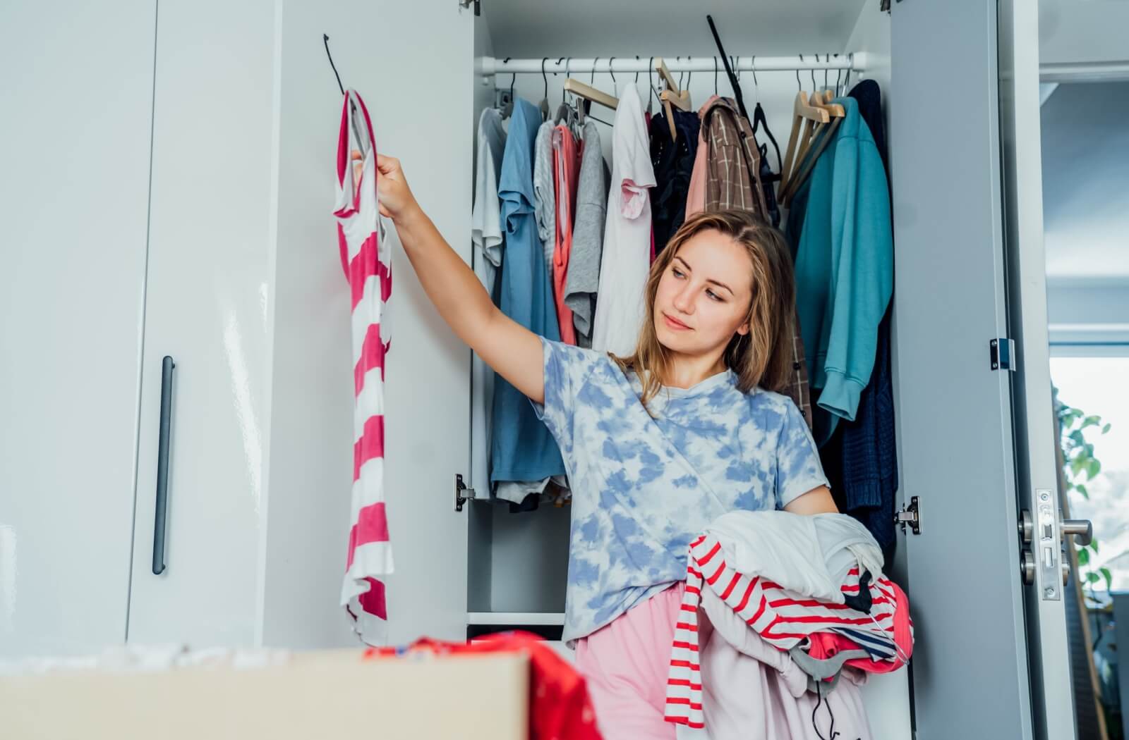 An adult goes through their wardrobe to find clothing they can donate to Regeneration Outreach Community.