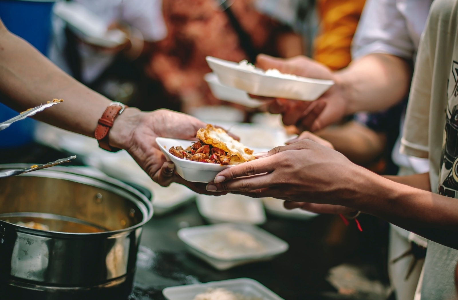 A volunteer serves a hot meal into a bowl at a community food bank.