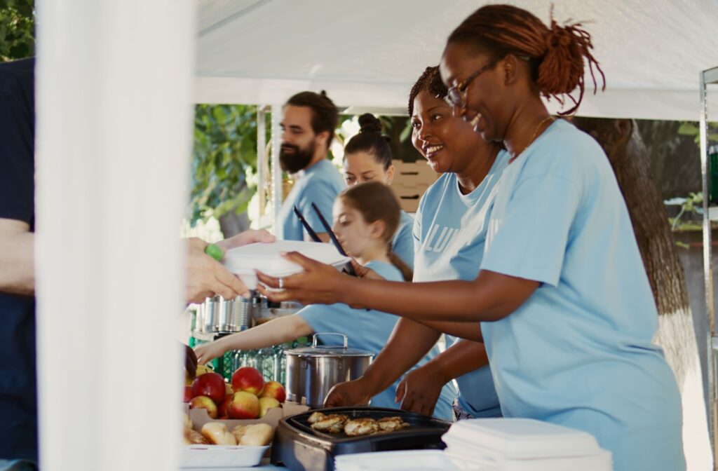 Group of volunteers smiling and helping to service food at a soup kitchen